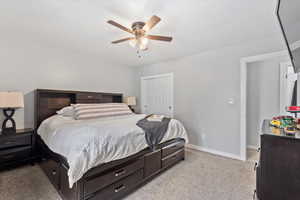 Bedroom with a closet, light carpet, and ceiling fan