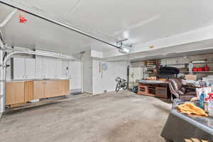 Garage featuring white refrigerator with ice dispenser and a garage door opener