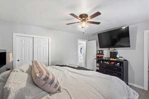 Carpeted bedroom with a closet and a ceiling fan