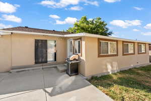 Property entrance featuring stucco siding, a patio, and a lawn