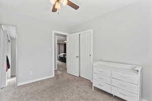 Unfurnished bedroom with light colored carpet and ceiling fan
