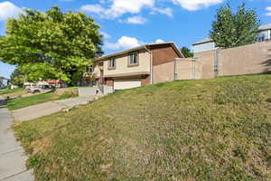 View of front of house featuring an attached garage, a gate, concrete driveway, and brick siding
