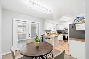 Dining area with french doors, light tile patterned floors, and light colored carpet
