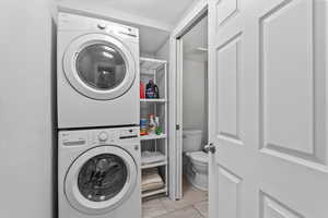 Laundry room featuring light tile patterned flooring and stacked washer / dryer