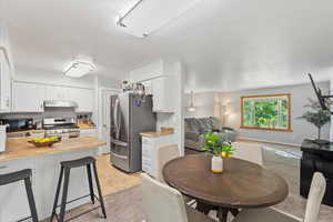 Kitchen with white cabinetry, a breakfast bar, stainless steel appliances, light tile patterned floors, and open floor plan