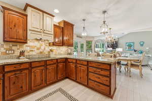 Kitchen featuring a peninsula, light stone countertops, tasteful backsplash, pendant lighting, and open floor plan