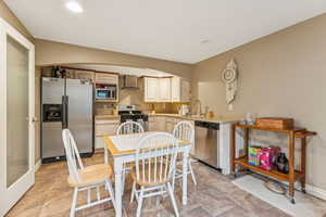 Kitchen with light countertops, stainless steel appliances, wall chimney range hood, recessed lighting, and light brown cabinetry