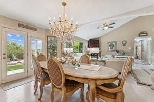 Dining room with a chandelier, light wood-style floors, ceiling fan, beam ceiling, and high vaulted ceiling