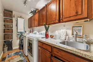 Laundry area featuring independent washer and dryer, light tile patterned floors, and cabinet space