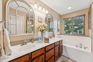 Bathroom with double vanity, a bath, light tile patterned floors, and recessed lighting