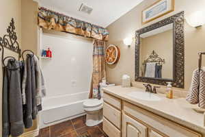 Bathroom featuring shower / bath combo, vanity, and dark tile patterned floors