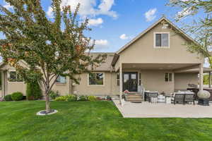 Rear view of house with a patio, a yard, and stucco siding