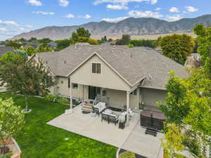 Rear view of property featuring roof with shingles, stucco siding, a patio area, and a mountain view