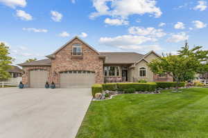 View of front of house with an attached garage, a porch, a front yard, driveway, and roof with shingles