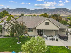 Back of house with a lawn, stucco siding, a hot tub, a patio, and a mountain view