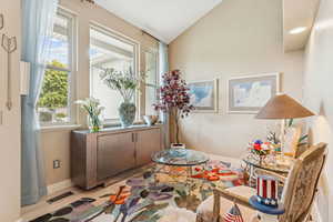 Living area featuring plenty of natural light, lofted ceiling, and light wood-style flooring
