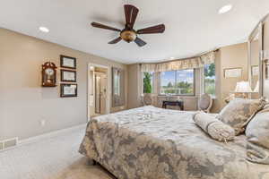 Bedroom featuring light colored carpet, recessed lighting, ceiling fan, and ensuite bath