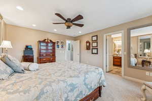 Bedroom featuring light colored carpet, ceiling fan, recessed lighting, and ensuite bath