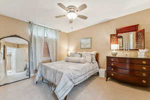 Bedroom with a ceiling fan, carpet, and arched walkways