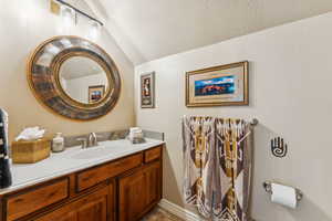 Bathroom featuring a textured ceiling, vanity, vaulted ceiling, and light tile patterned floors