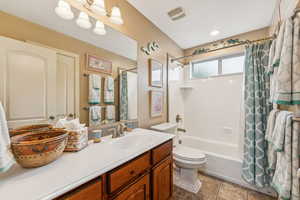 Bathroom featuring shower / bath combination with curtain, vanity, and light tile patterned floors
