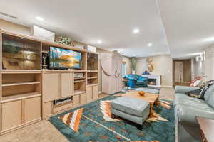 Living room featuring carpet, recessed lighting, and a warm lit fireplace