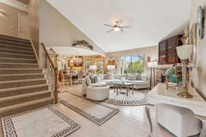 Living area with stairway, high vaulted ceiling, a chandelier, arched walkways, and ceiling fan