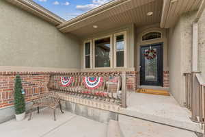 Entrance to property featuring stucco siding, brick siding, and a patio