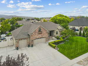View of front of house featuring roof with shingles, brick siding, driveway, an attached garage, and a mountain view