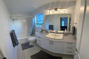 Full bathroom with shower / bathtub combination with curtain, vanity, and light wood-style floors