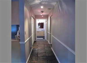 Hall featuring baseboards and dark stone finish flooring