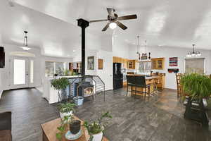 Living area featuring a wood stove, ceiling fan, dark wood-style tile, high vaulted ceiling, and a ceiling fan.