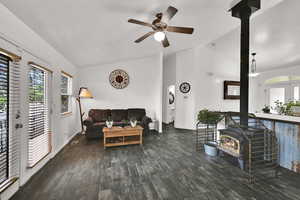 Living area featuring a wood stove, lofted ceiling, wood-style tile and a healthy amount of natural light.