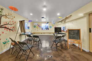 Recreation room with concrete flooring, a textured ceiling, and recessed lighting