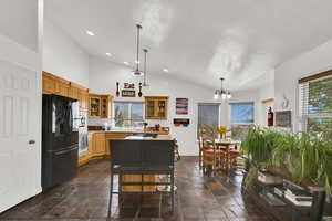 Kitchen featuring pendant lighting, black fridge with ice dispenser, glass insert cabinets, tile floors, and light countertops
