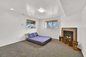 Bedroom with a tiled fireplace, carpet, a textured ceiling, and recessed lighting