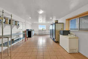 Kitchen with a textured ceiling, appliances with stainless steel finishes, light tile patterned flooring, and recessed lighting