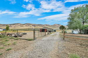 View of dirt / gravel road with a mountain view, a view of rural / pastoral area, an exterior structure.