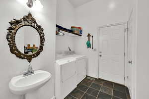 Laundry room with independent washer and dryer and dark tile patterned floors