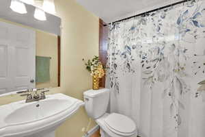Full bath featuring a shower with curtain and a textured ceiling