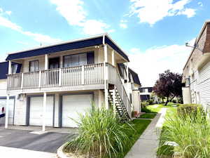 View of front of property featuring a garage, stairway, asphalt driveway, and covered porch