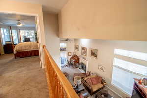 Carpeted bedroom with a glass covered fireplace and a towering ceiling