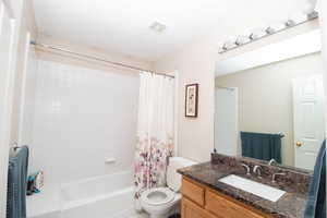 Bathroom with shower / bath combo with shower curtain, vanity, and tile patterned flooring