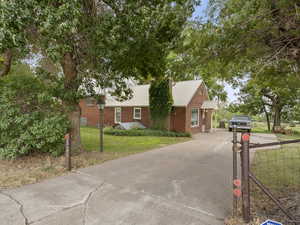 Single story home with a front yard, a metal roof, driveway, brick siding, and a chimney