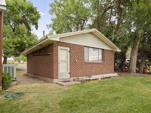 Rear view of house featuring a lawn and brick siding
