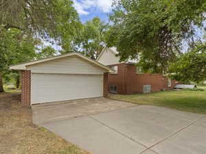 View of home's exterior featuring brick siding, a yard, and driveway