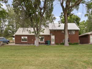 Rear view of house featuring a yard, a metal roof, and brick siding