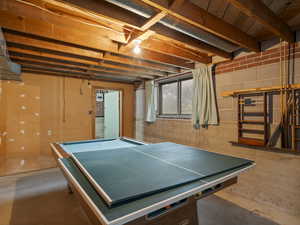 Rec room with unfinished concrete flooring and billiards table