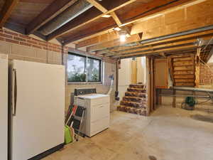 Below grade area featuring stairs, freestanding refrigerator, and washer / clothes dryer