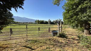 View of grassy yard featuring a mountain view, a gate, and a view of countryside